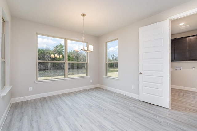 unfurnished dining area featuring a notable chandelier and light hardwood / wood-style flooring