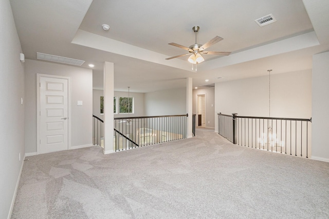 carpeted spare room featuring a raised ceiling and ceiling fan