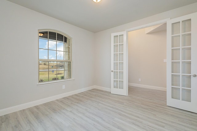 empty room with light hardwood / wood-style floors and french doors