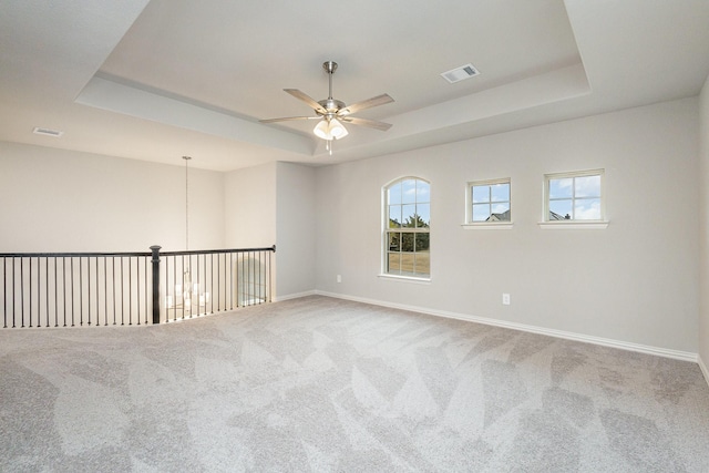 carpeted empty room featuring ceiling fan and a raised ceiling