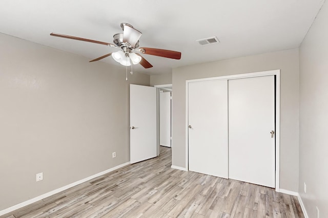 unfurnished bedroom with ceiling fan, light wood-type flooring, and a closet