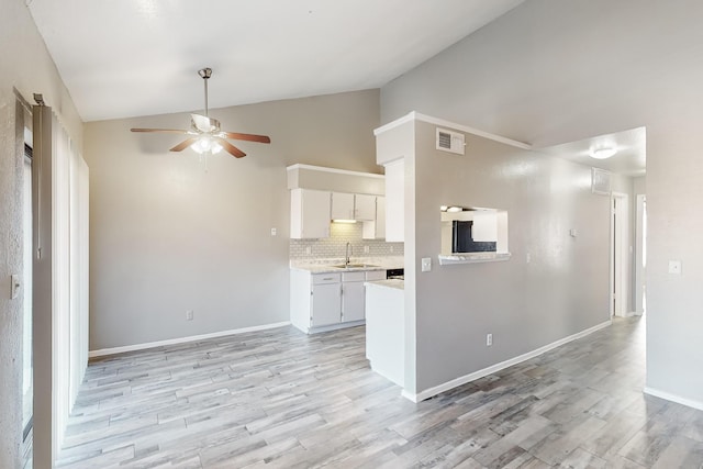 kitchen featuring white cabinetry, vaulted ceiling, light hardwood / wood-style flooring, and decorative backsplash