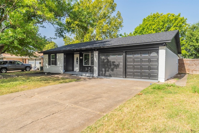 single story home featuring concrete driveway, a front lawn, an attached garage, brick siding, and roof with shingles