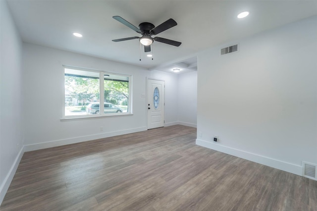 empty room featuring wood finished floors, visible vents, baseboards, and ceiling fan