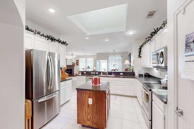 kitchen with white cabinetry, stainless steel appliances, kitchen peninsula, and a center island