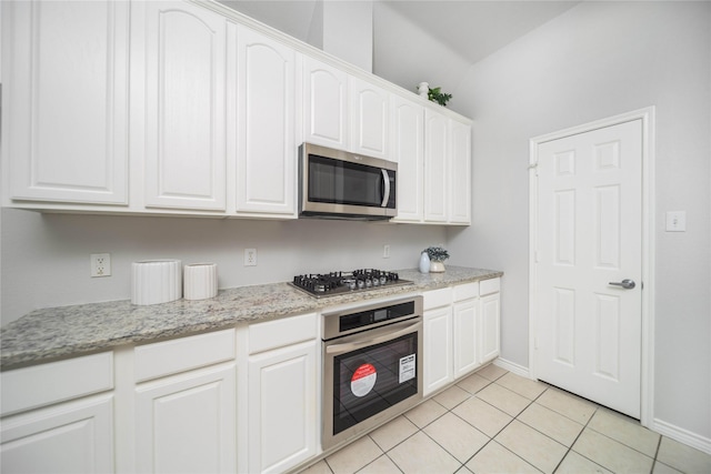 kitchen with light stone counters, appliances with stainless steel finishes, light tile patterned floors, and white cabinets