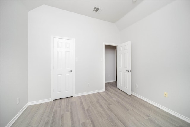 unfurnished bedroom featuring vaulted ceiling and light wood-type flooring