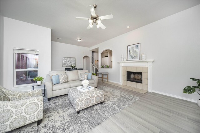 living room featuring a tile fireplace, hardwood / wood-style flooring, and ceiling fan