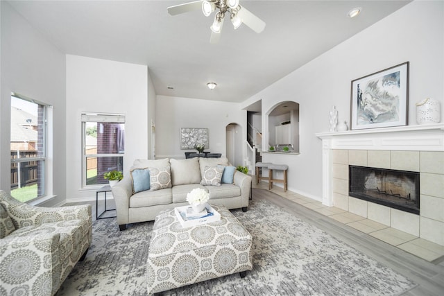 living room featuring ceiling fan, hardwood / wood-style floors, and a tile fireplace