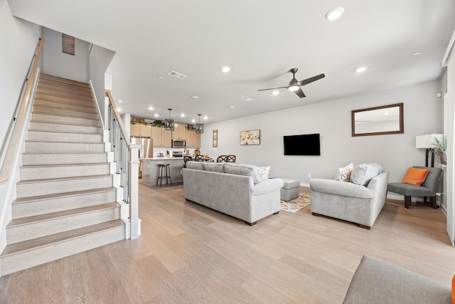 living room with light hardwood / wood-style floors and ceiling fan