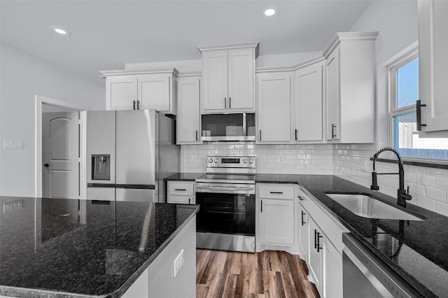 kitchen with dark stone counters, white cabinetry, sink, and stainless steel appliances