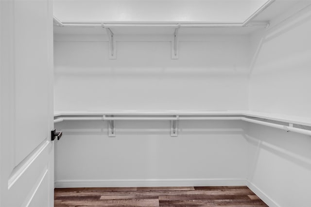 walk in closet with dark wood-type flooring