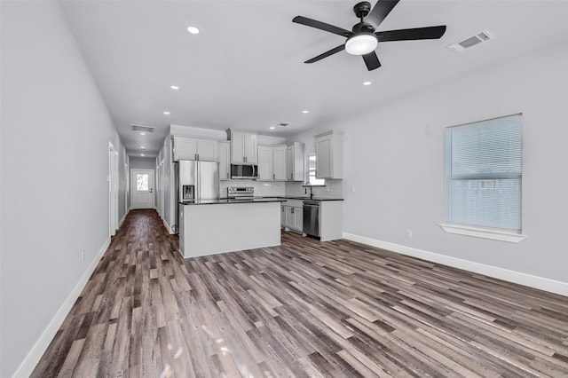 kitchen featuring white cabinetry, ceiling fan, stainless steel appliances, backsplash, and wood-type flooring