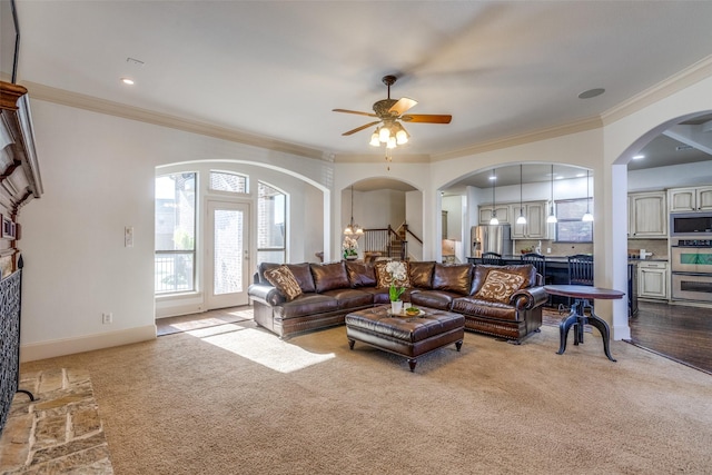 living room with ceiling fan, light colored carpet, and ornamental molding