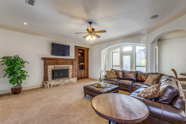 carpeted living room featuring a fireplace, ceiling fan, and crown molding