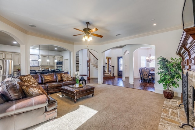 carpeted living room with ceiling fan with notable chandelier and ornamental molding