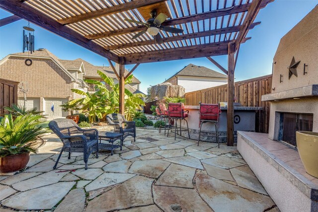 view of patio with a fireplace, a pergola, an outdoor bar, and ceiling fan