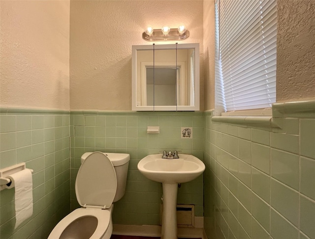 bathroom with toilet and tile walls