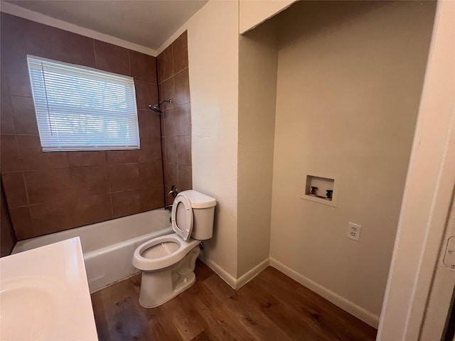 bathroom featuring tiled shower / bath, wood-type flooring, and toilet