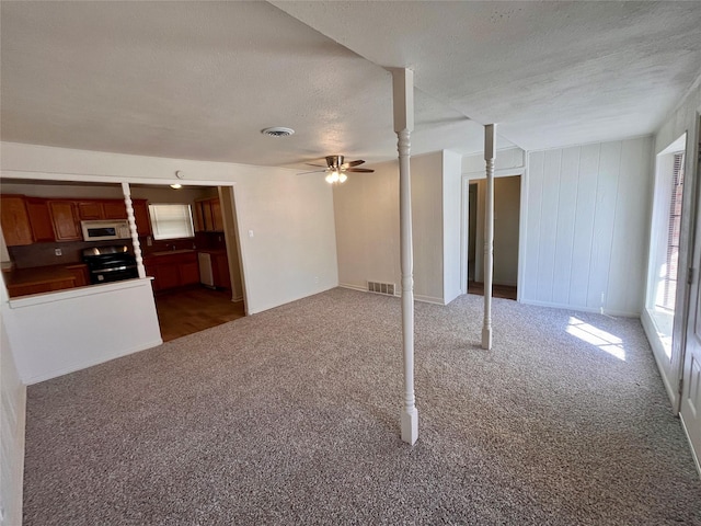 unfurnished living room featuring ceiling fan, dark carpet, and a textured ceiling