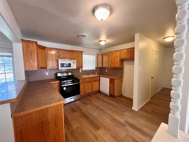 kitchen featuring tasteful backsplash, plenty of natural light, white appliances, and light hardwood / wood-style flooring