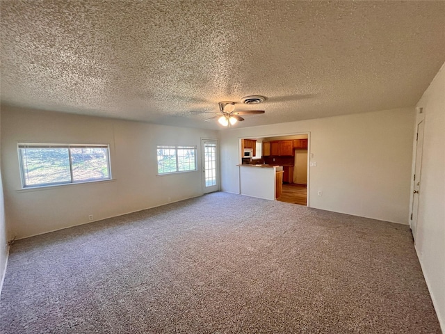 unfurnished living room with ceiling fan, light colored carpet, and a textured ceiling