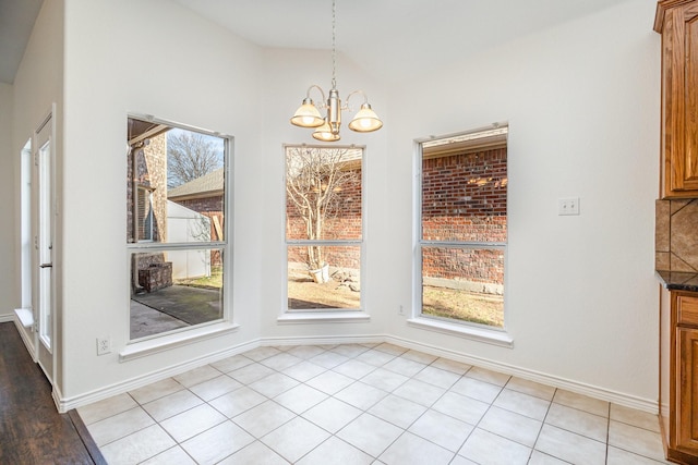 unfurnished dining area with lofted ceiling, light tile patterned floors, and a notable chandelier