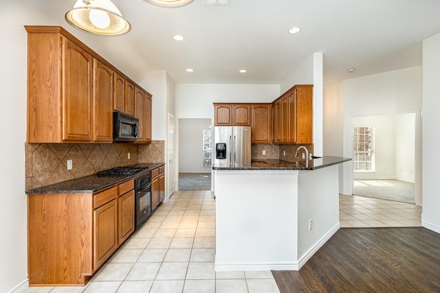 kitchen featuring decorative light fixtures, dark stone countertops, kitchen peninsula, and black appliances