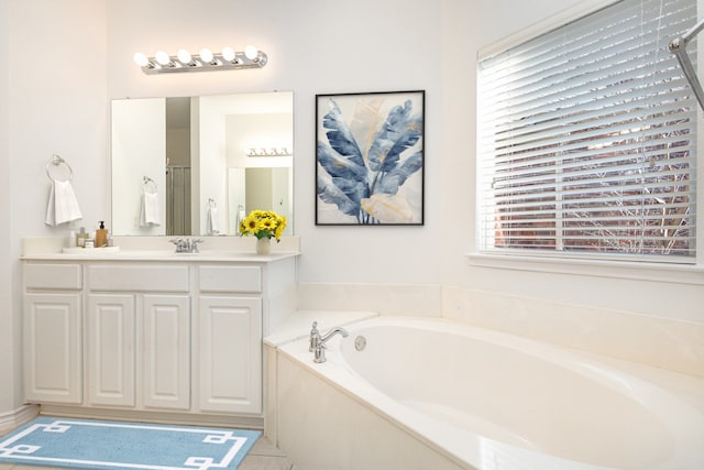 bathroom featuring tile patterned flooring, vanity, a healthy amount of sunlight, and tiled bath