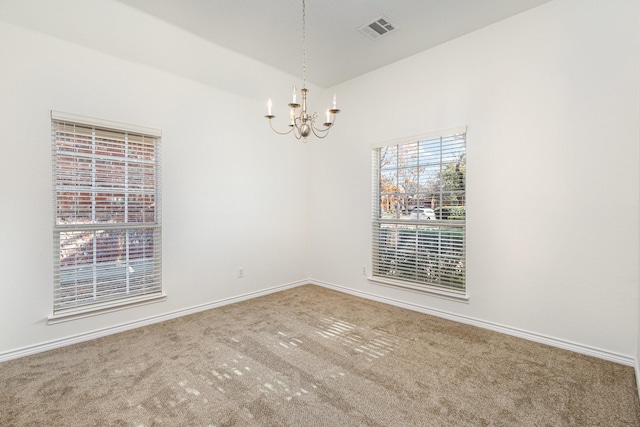 carpeted spare room with a chandelier