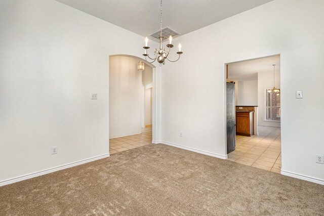 unfurnished room featuring light carpet and a notable chandelier