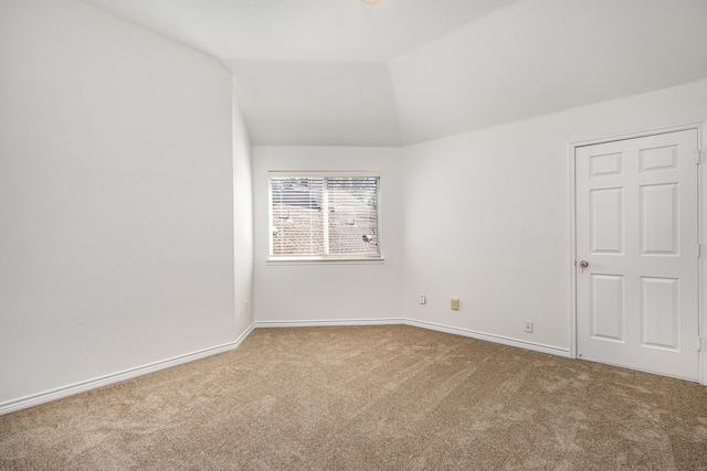 carpeted empty room with lofted ceiling