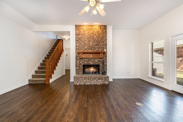 unfurnished living room featuring a brick fireplace, dark wood-type flooring, and ceiling fan