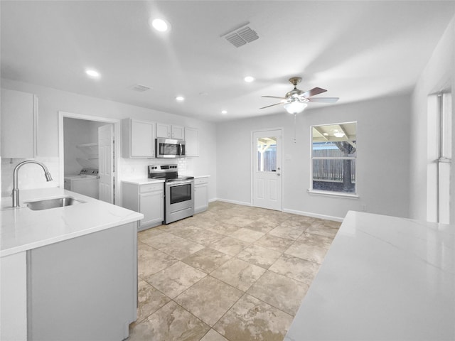 kitchen featuring washer / clothes dryer, sink, white cabinets, ceiling fan, and stainless steel appliances