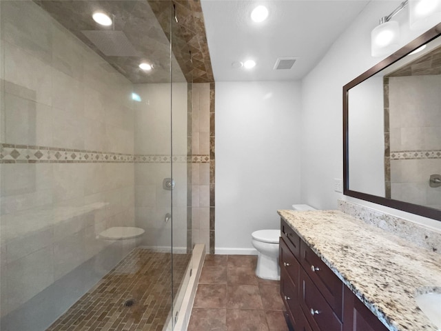 bathroom with vanity, toilet, tile patterned flooring, and a tile shower