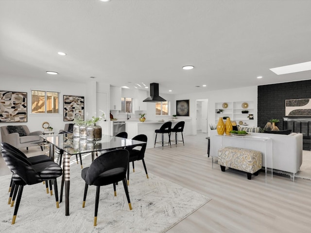 dining space featuring built in shelves, a fireplace, and light hardwood / wood-style flooring