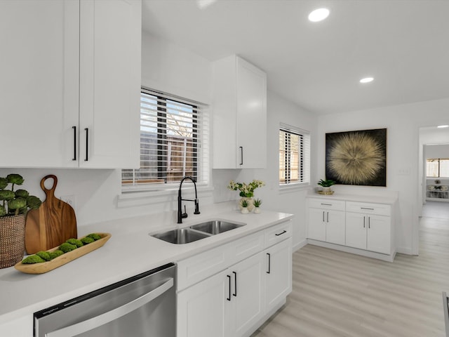 kitchen featuring white cabinetry, dishwasher, sink, and light hardwood / wood-style floors