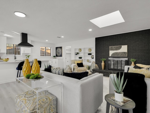 living room with a skylight, built in features, and light hardwood / wood-style flooring