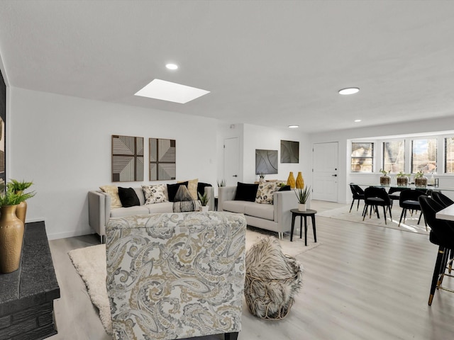 living room featuring a skylight and light hardwood / wood-style flooring