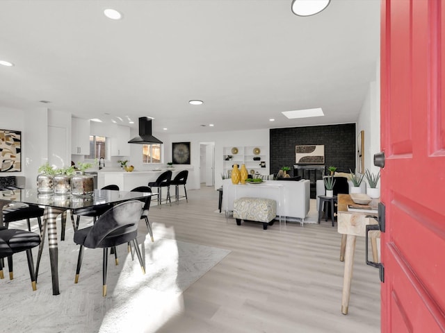 dining area with light wood-type flooring, a brick fireplace, and sink