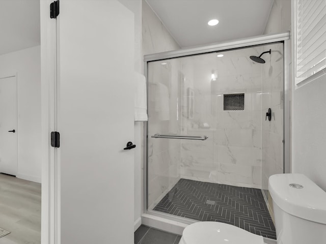 bathroom featuring a shower with shower door and toilet