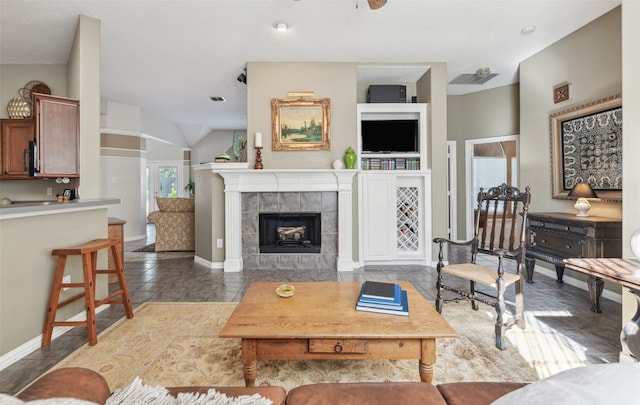 living room featuring ceiling fan, a healthy amount of sunlight, and a tiled fireplace