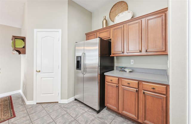 kitchen with stainless steel fridge, light tile patterned floors, and a textured ceiling