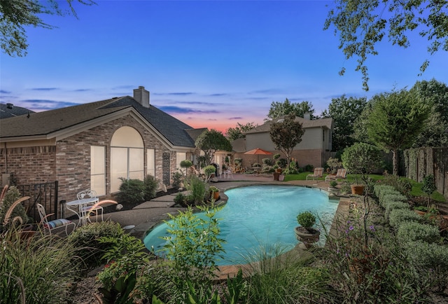 pool at dusk featuring a patio