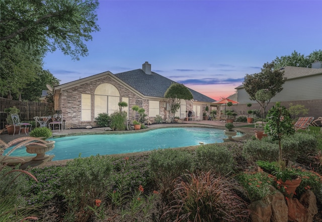 pool at dusk featuring a patio area and a jacuzzi