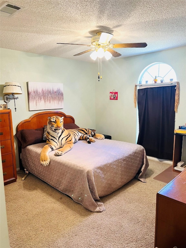 carpeted bedroom with a textured ceiling and ceiling fan