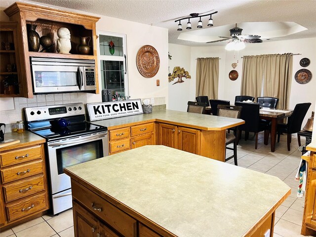 kitchen with a kitchen bar, stainless steel appliances, tasteful backsplash, a textured ceiling, and a kitchen island