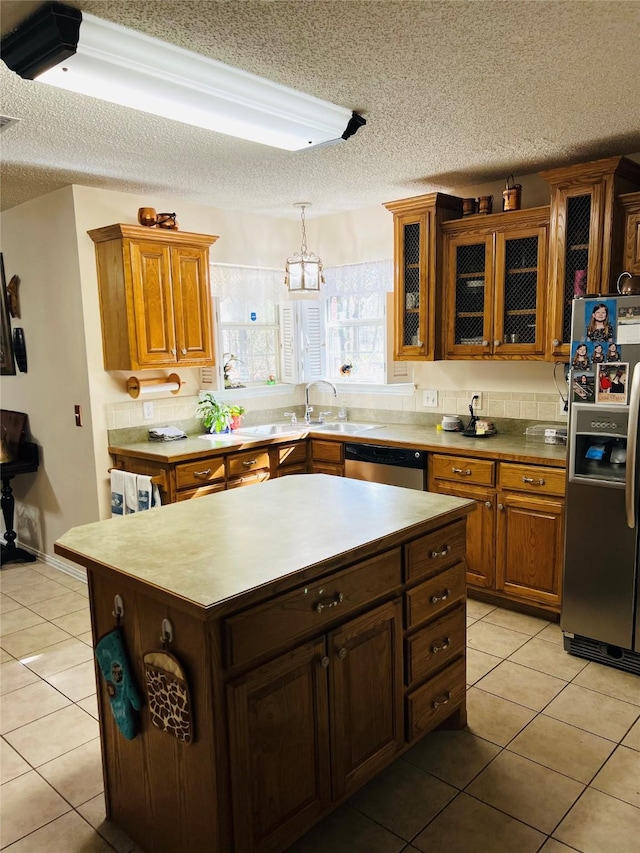 kitchen featuring pendant lighting, stainless steel appliances, a kitchen island, and light tile patterned floors