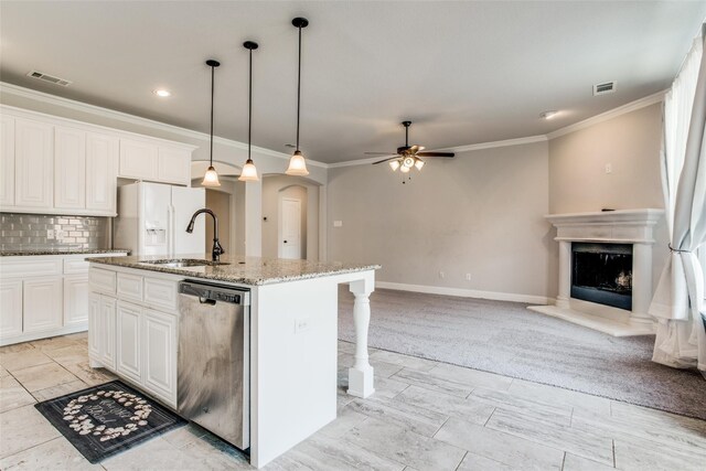 kitchen featuring decorative light fixtures, white cabinets, a kitchen island with sink, stainless steel dishwasher, and light stone countertops