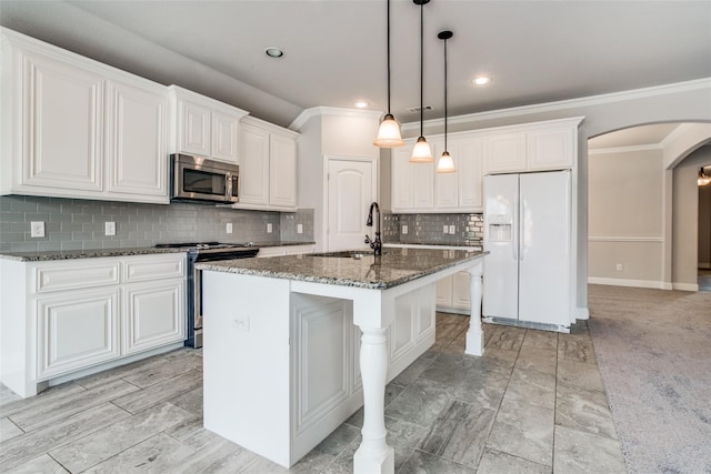 kitchen featuring a kitchen island with sink, sink, stainless steel appliances, and white cabinets